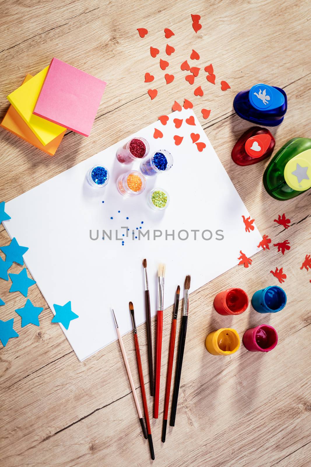 Top view of a designer workspace with blank paper and different colors and accessories. 