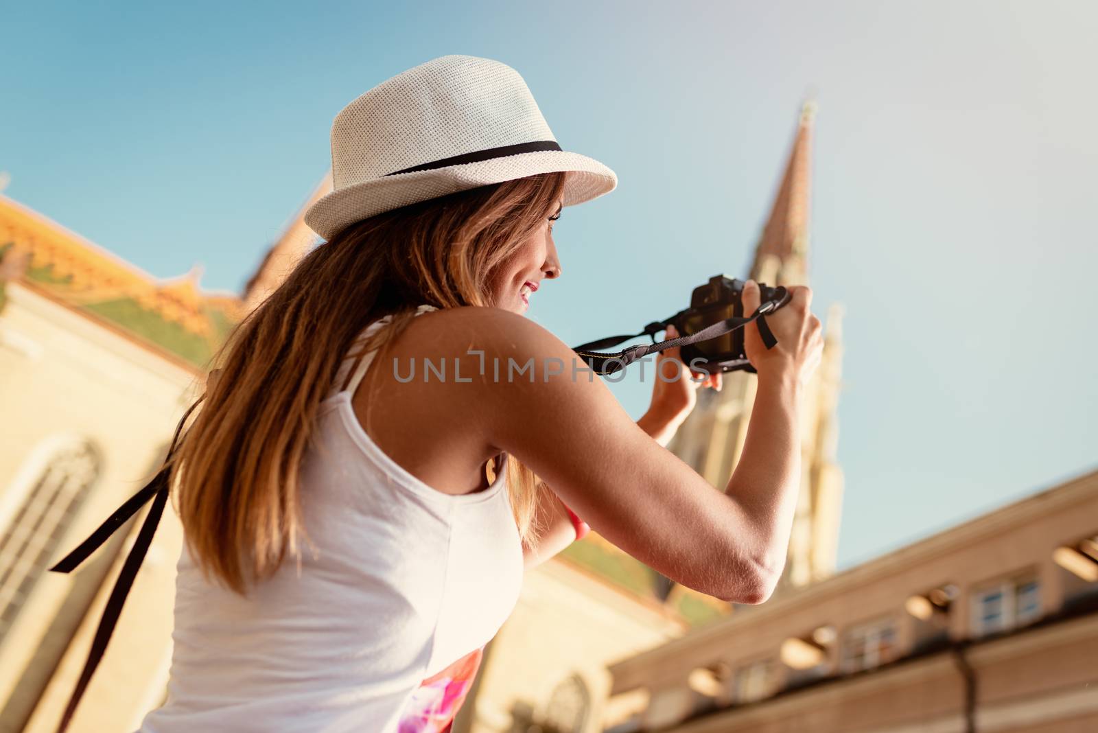 Beautiful smiling girl photographing architecture with digital camera in the city.