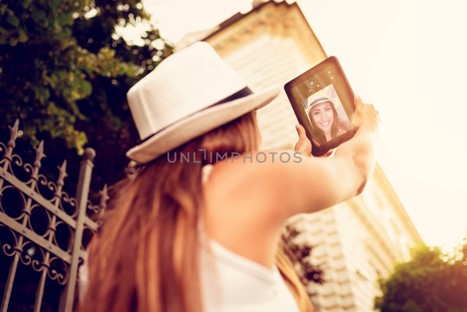 Beautiful young woman on vacations taking selfie with dogital tablet at the city square.