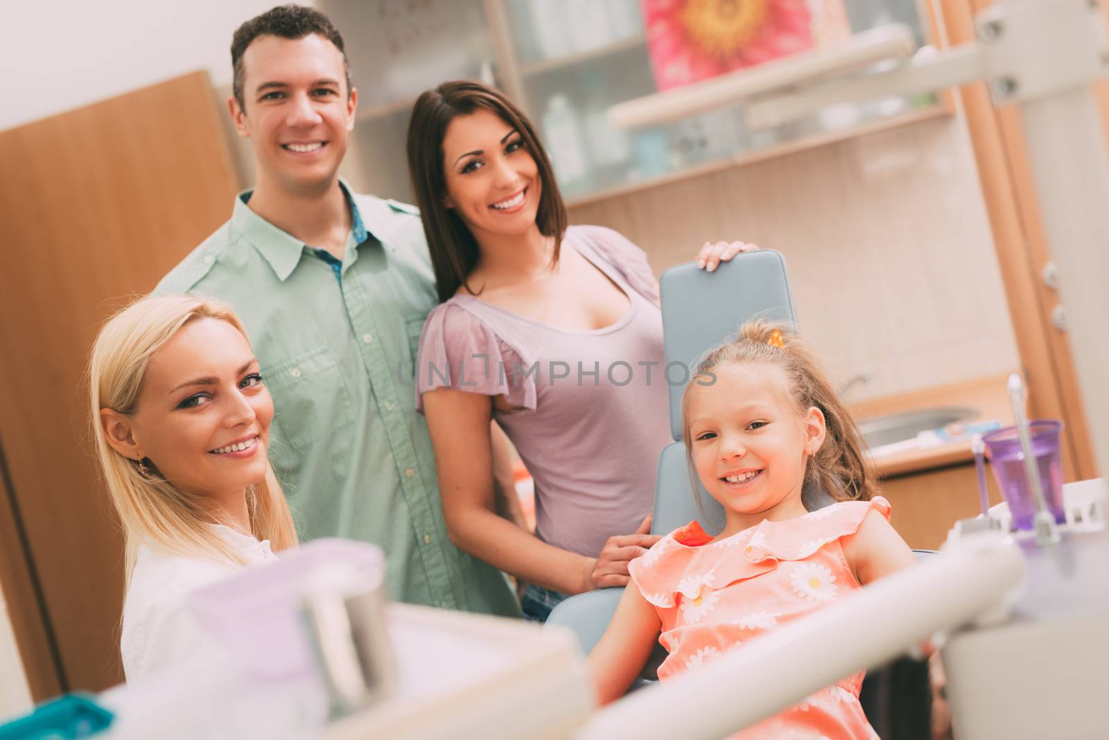 Happy young family at visit in the dentist office. They are  looking at camera.