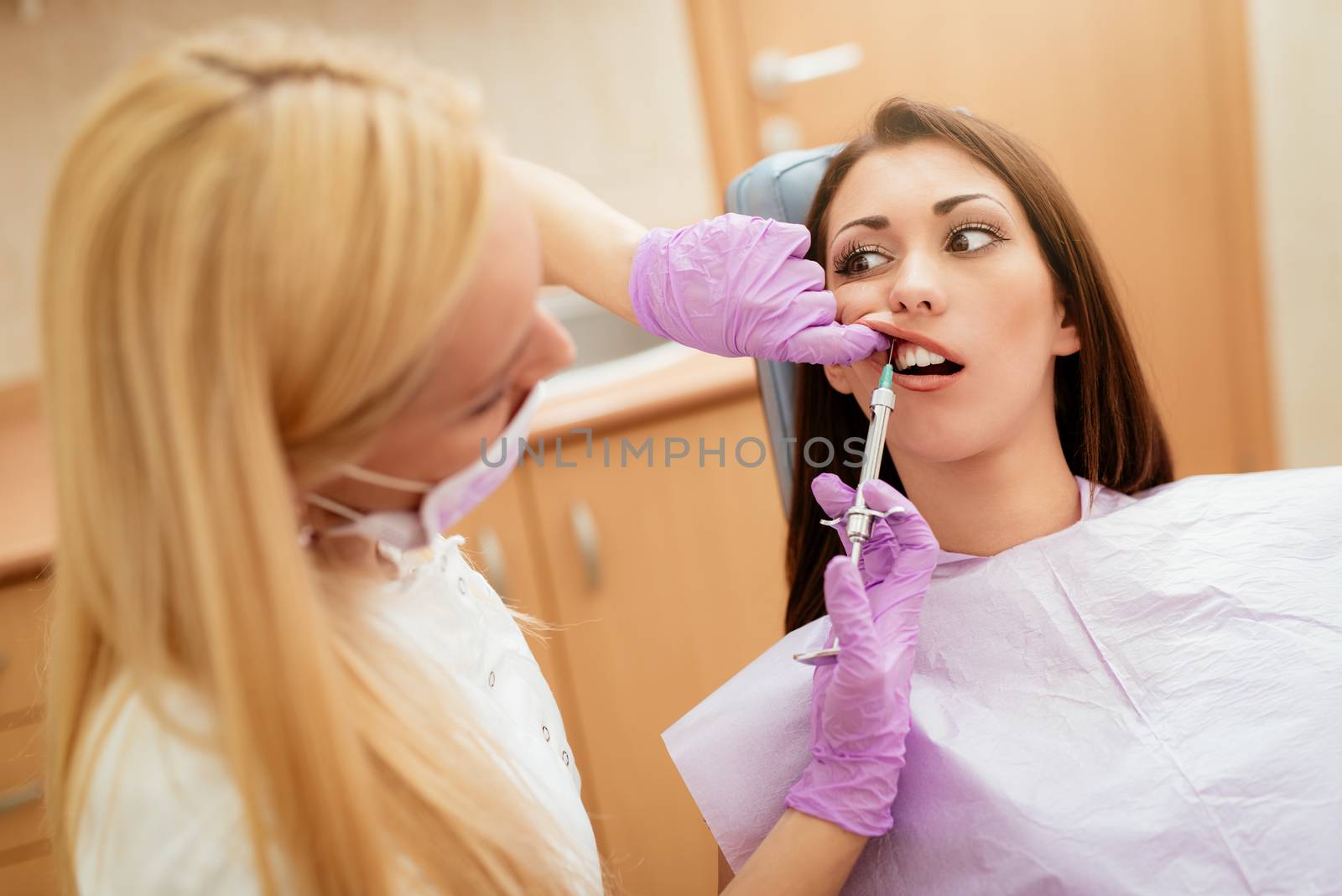 Dentist giving an injection of anesthesia to the female patient before dental treatment. Selective focus.