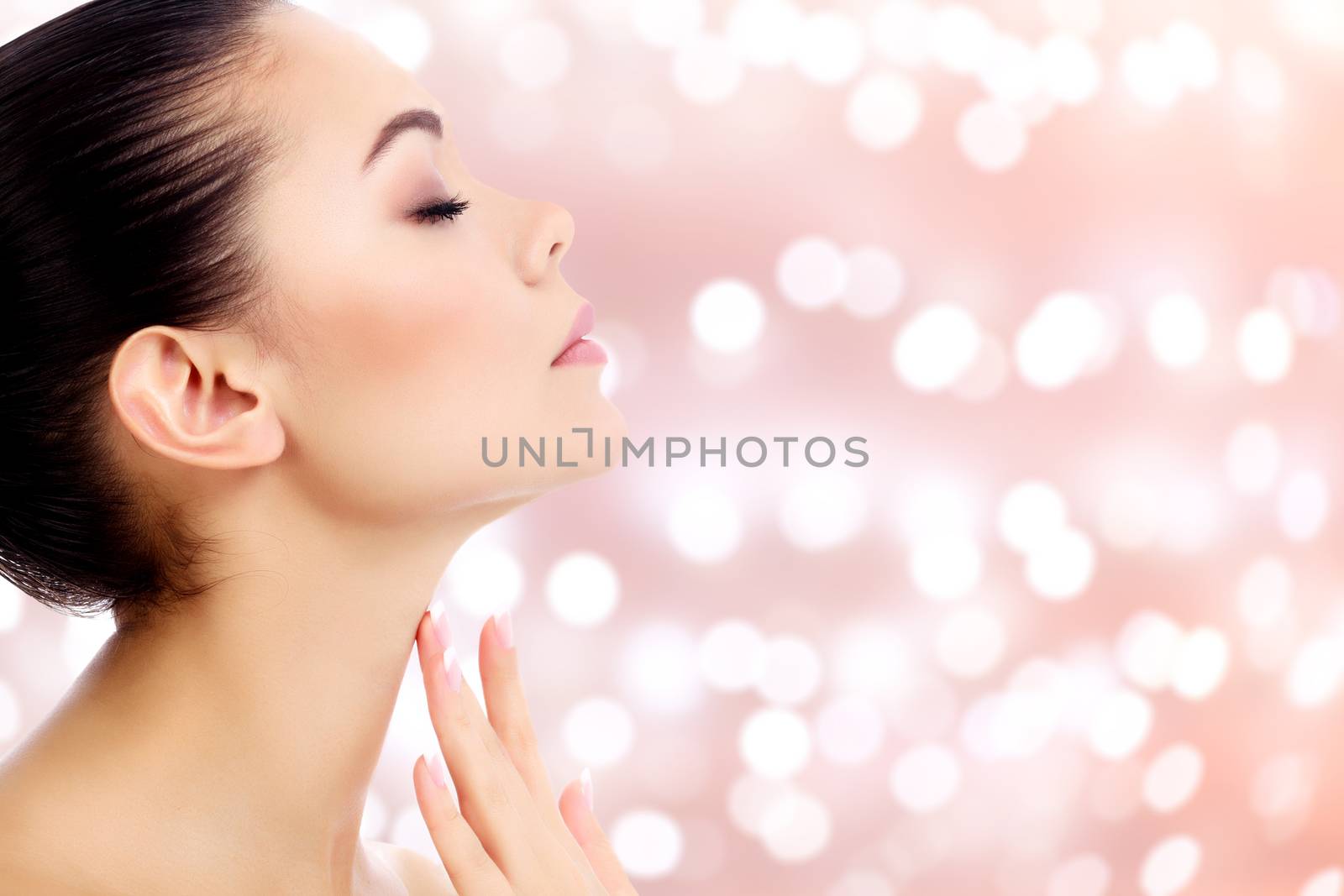 Young female touches her neck on an abstract background with blurred lights