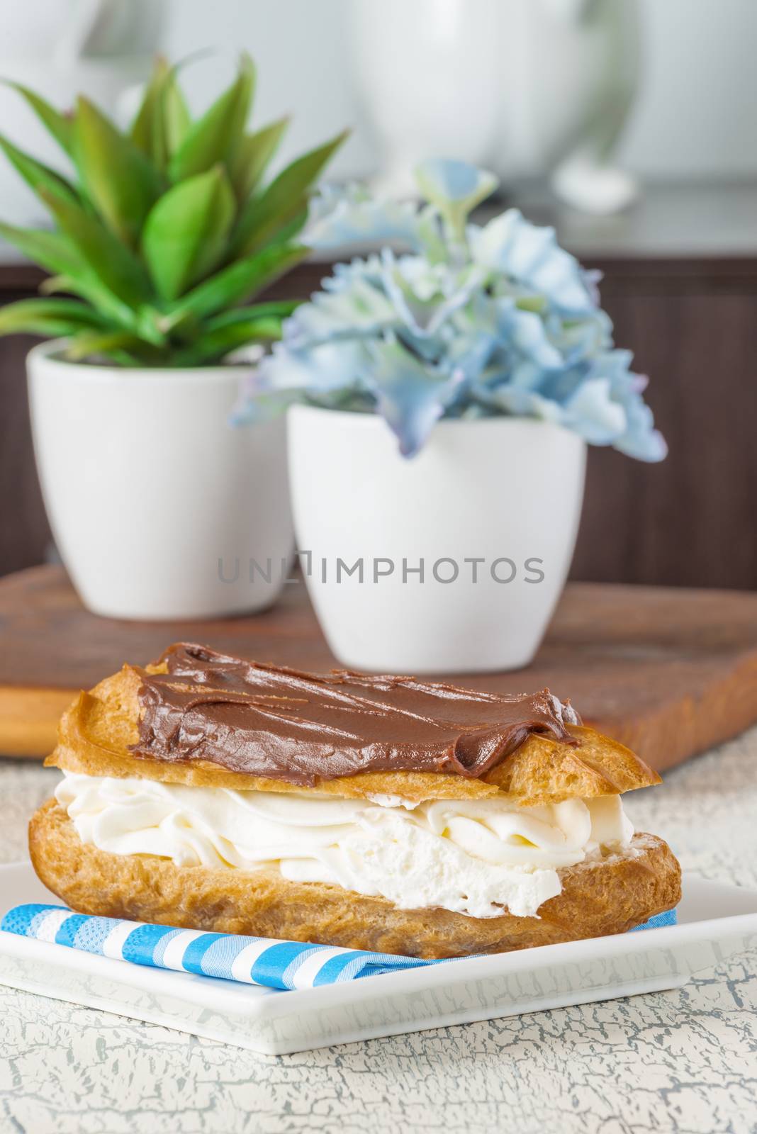 Closeup view of a delicious chocolate eclair with fresh whipped cream.