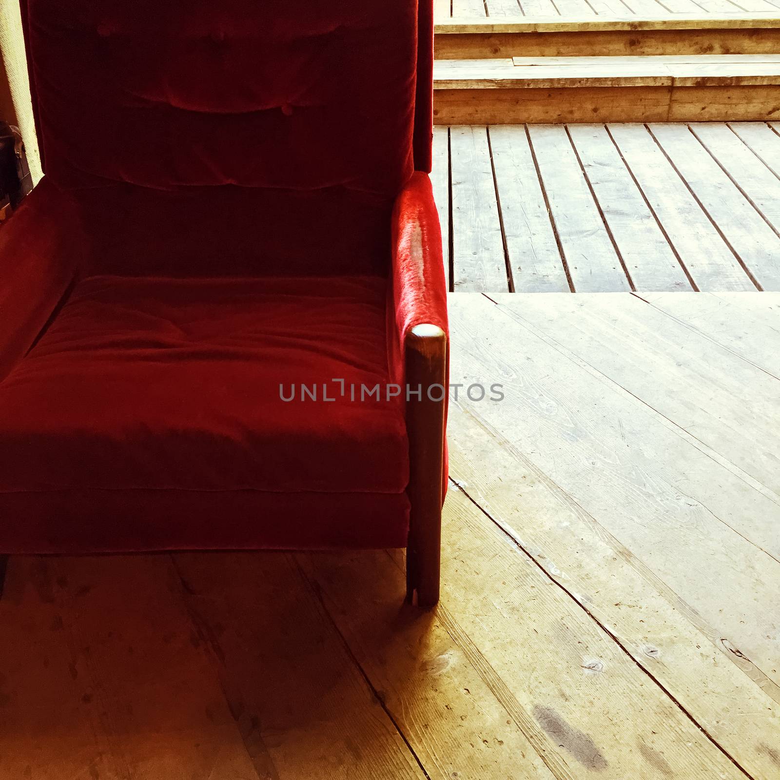 Rustic interior with vintage red velvet armchair and old wooden floor.