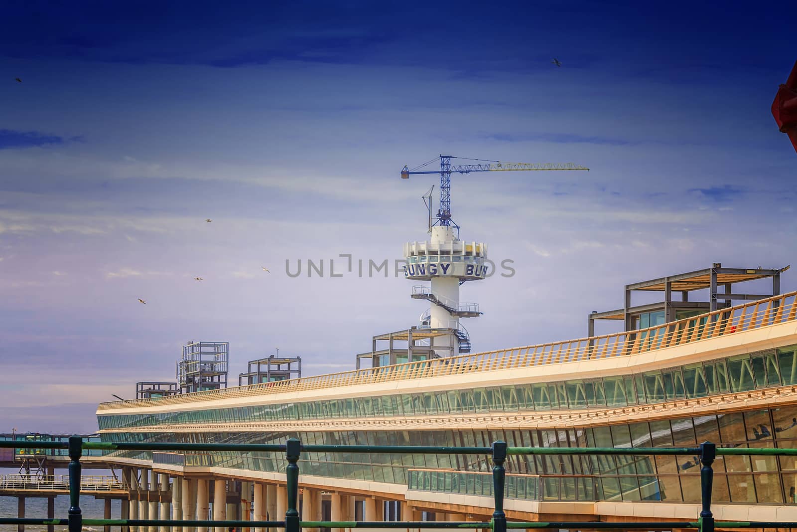 The pier of Scheveningen in the Netherlandsan a sunny day with blue sky in the background.