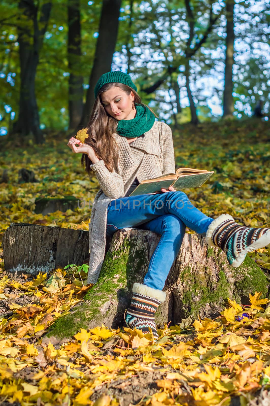 smiling, happy girl sitting on a stump in the autumn park