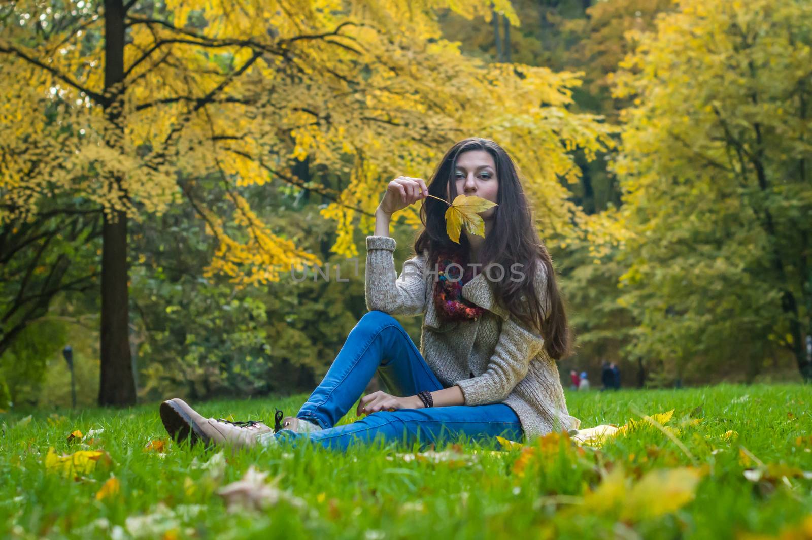 smiling, happy girl sitting on green grass in autumn park