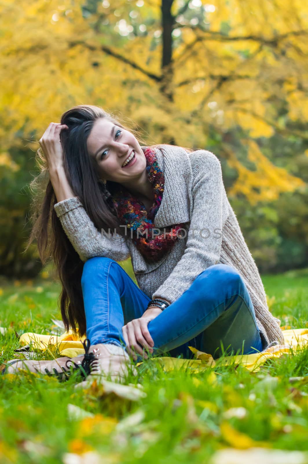 smiling, happy girl sitting on green grass in autumn park