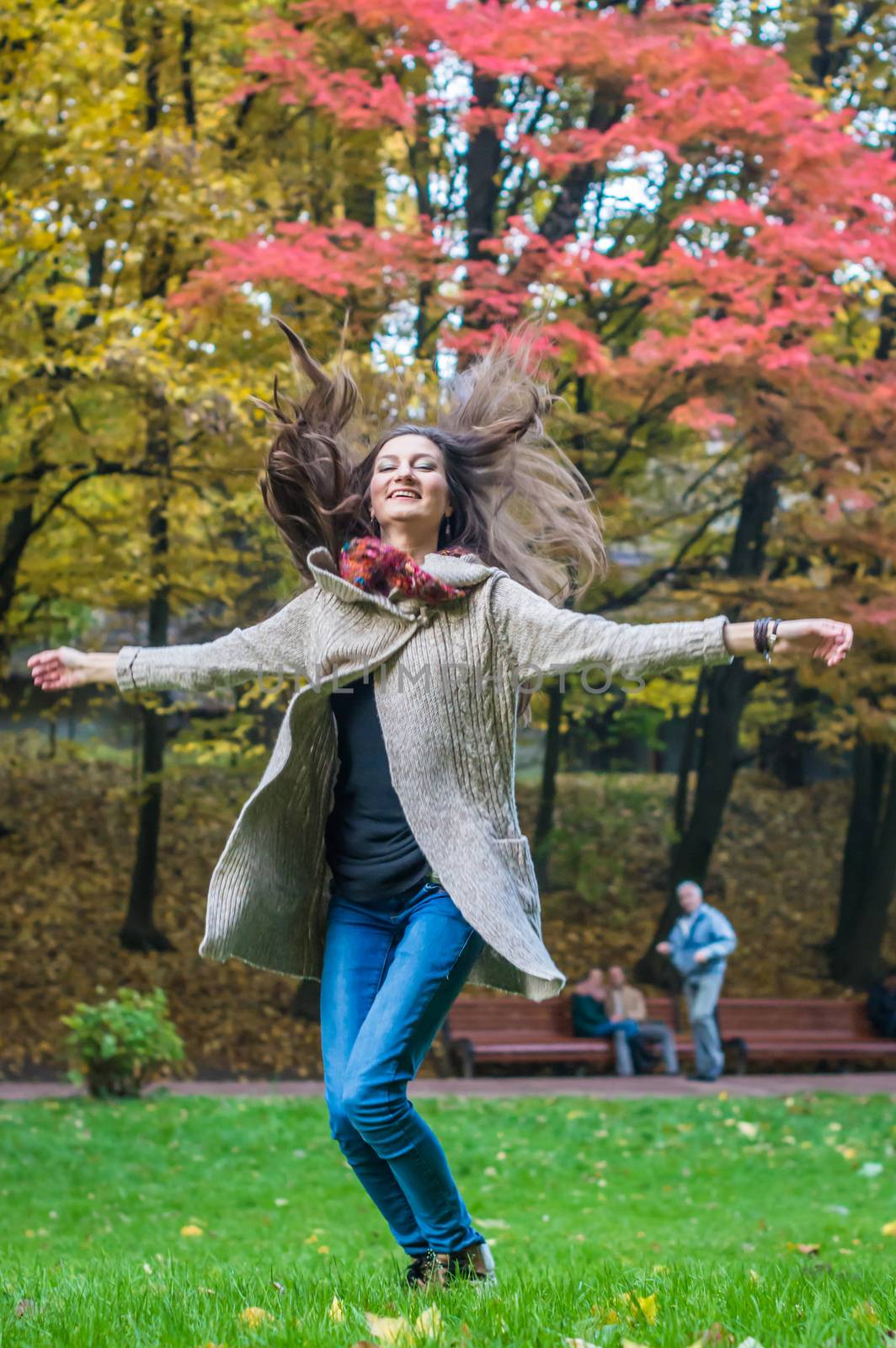 smiling, happy girl jumping on green grass in autumn park