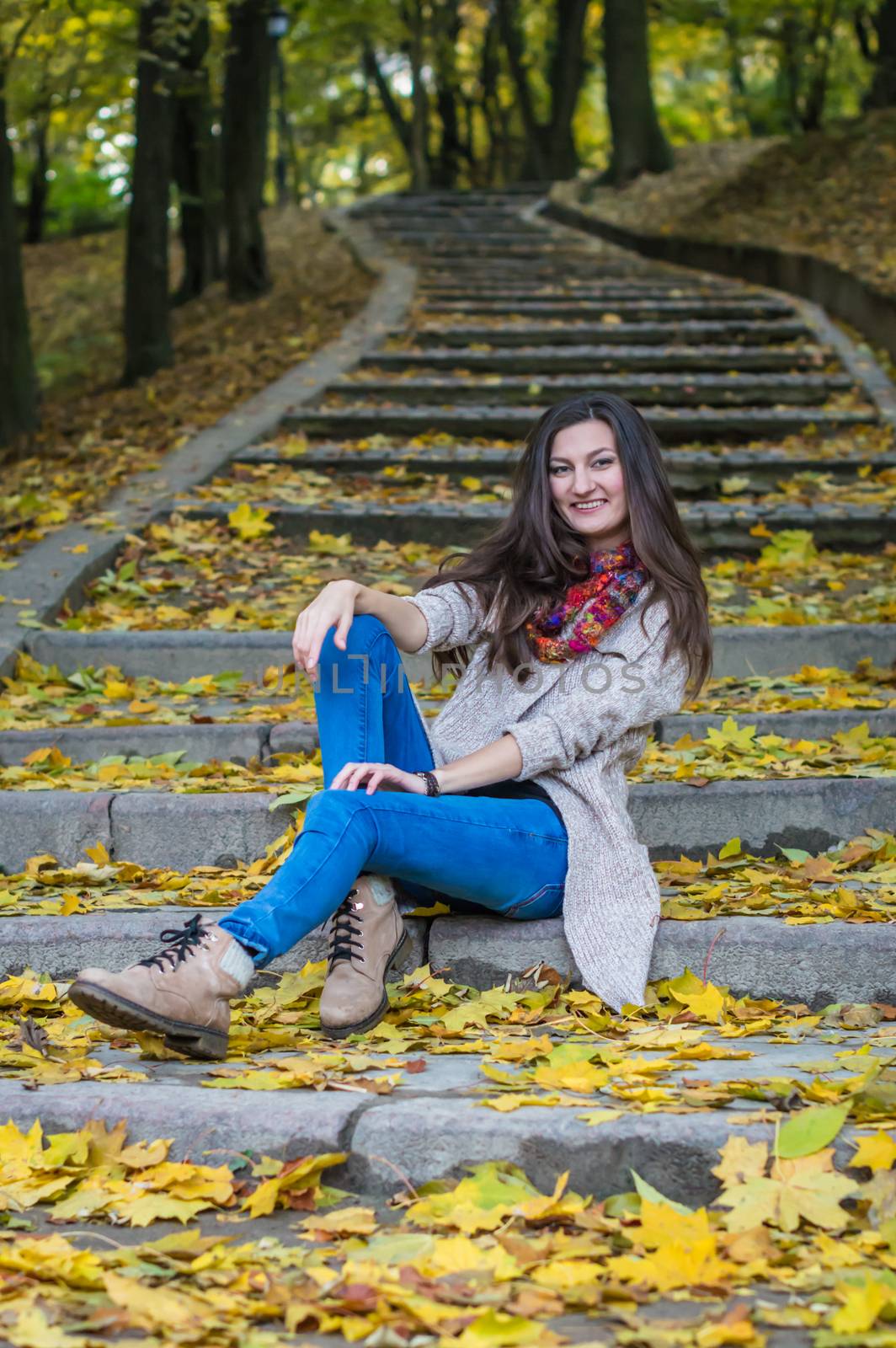 smiling, happy girl sitting on the stairs in the autumn park