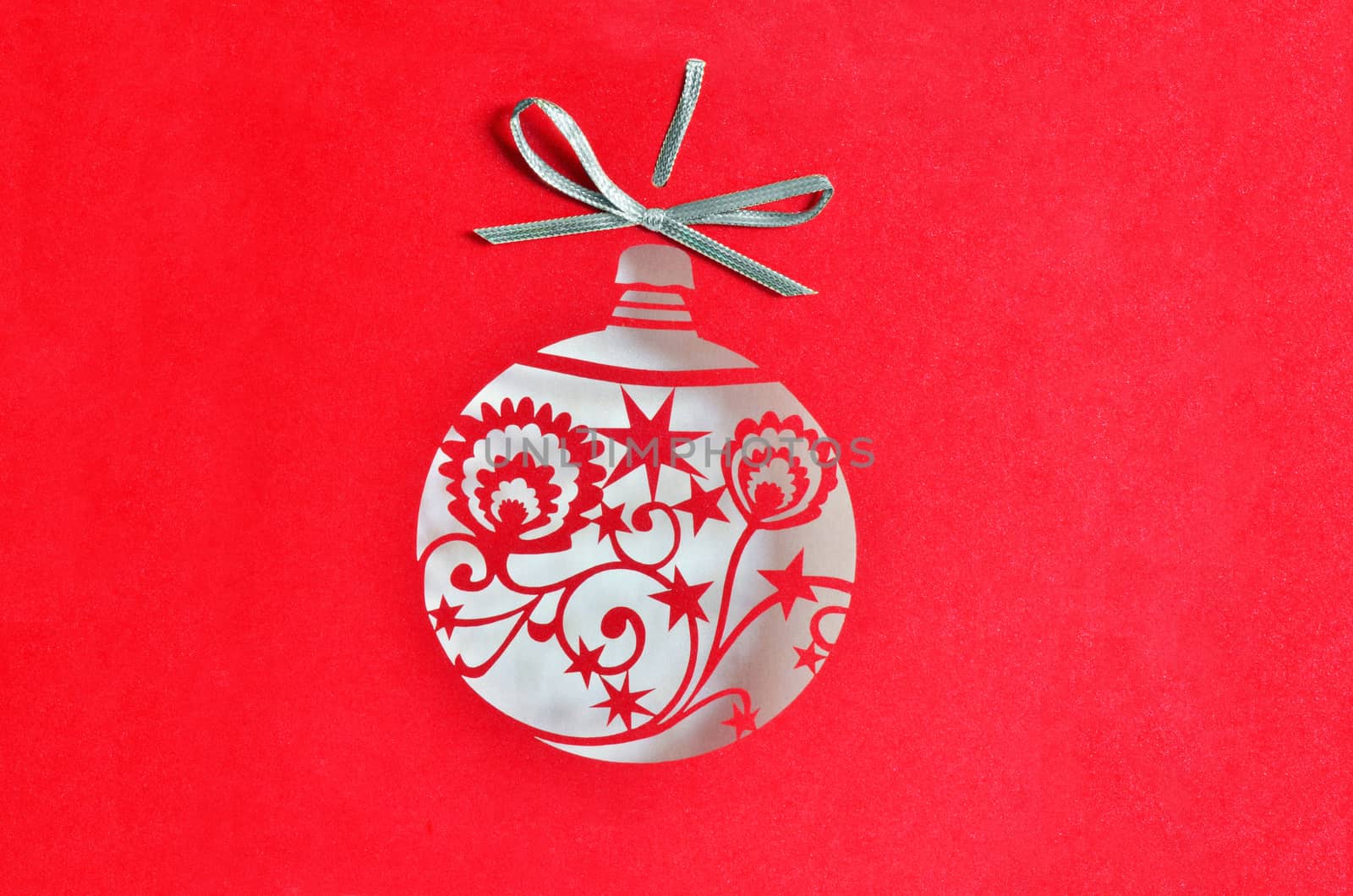 Christmas ball decoration on red glittering background. Sticked silver ribbon on top.