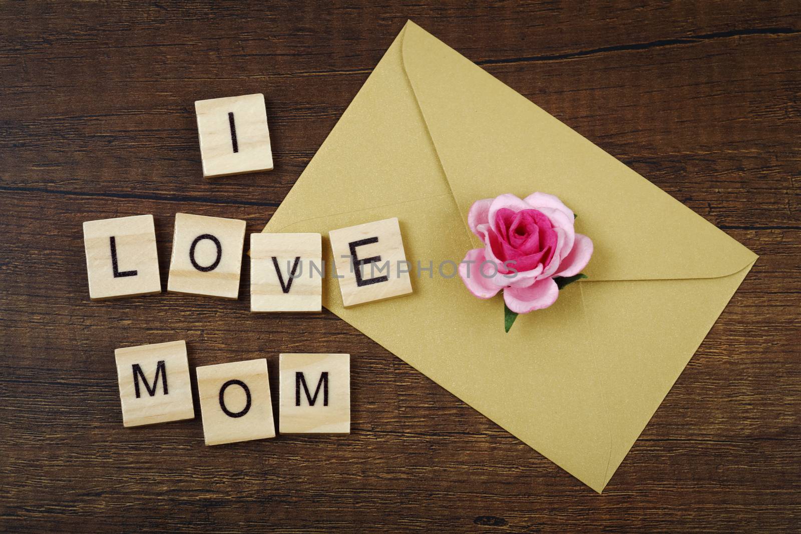 I love mom wording with pink rose flower sign and envelope on old wooden background, Mother's day concept.