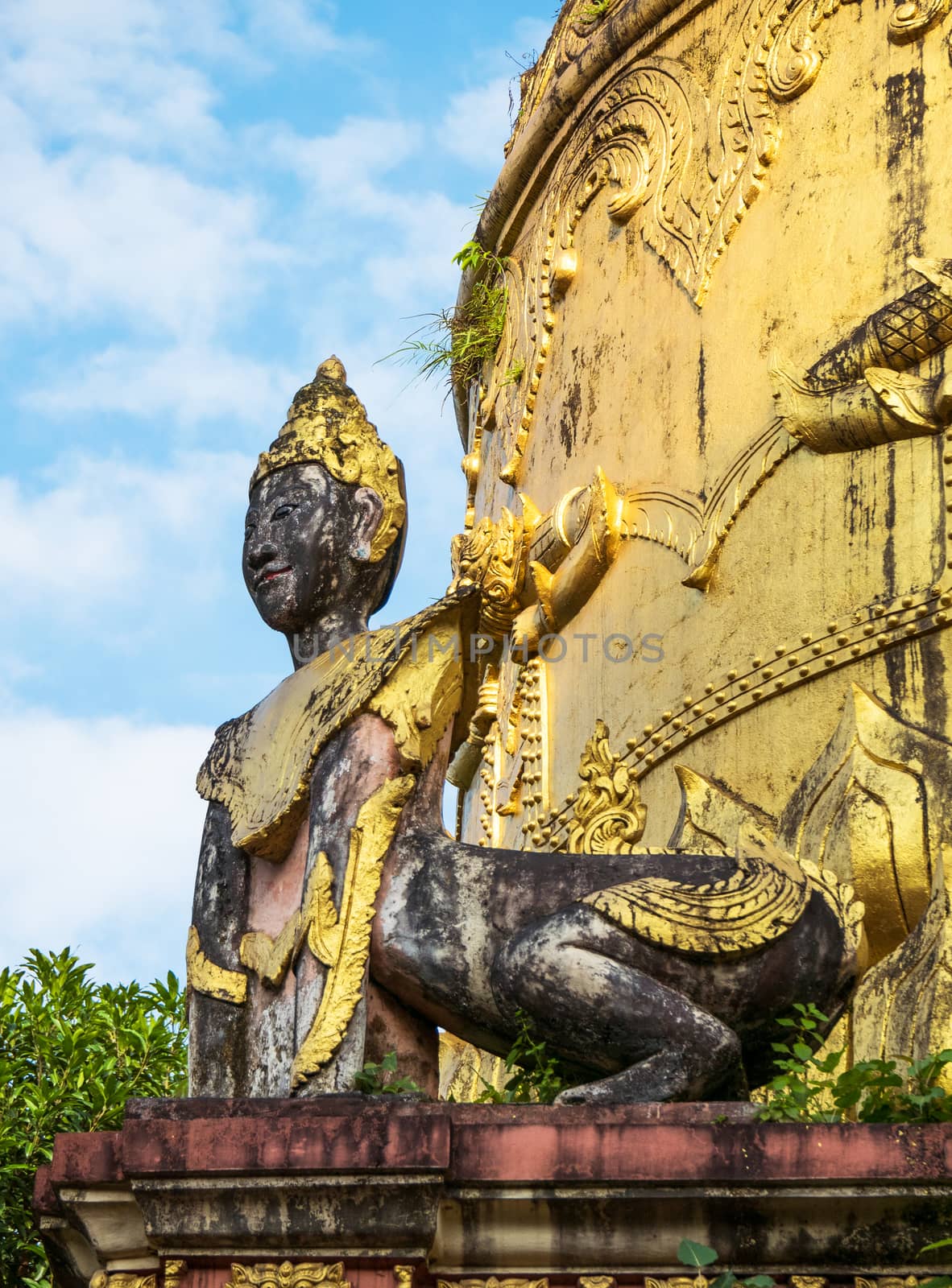Detail of old pagoda at the Moe Hnying Monastery in Yangon, Myanmar. Sculpture of hybrid creature with human head and animal body in the foreground.