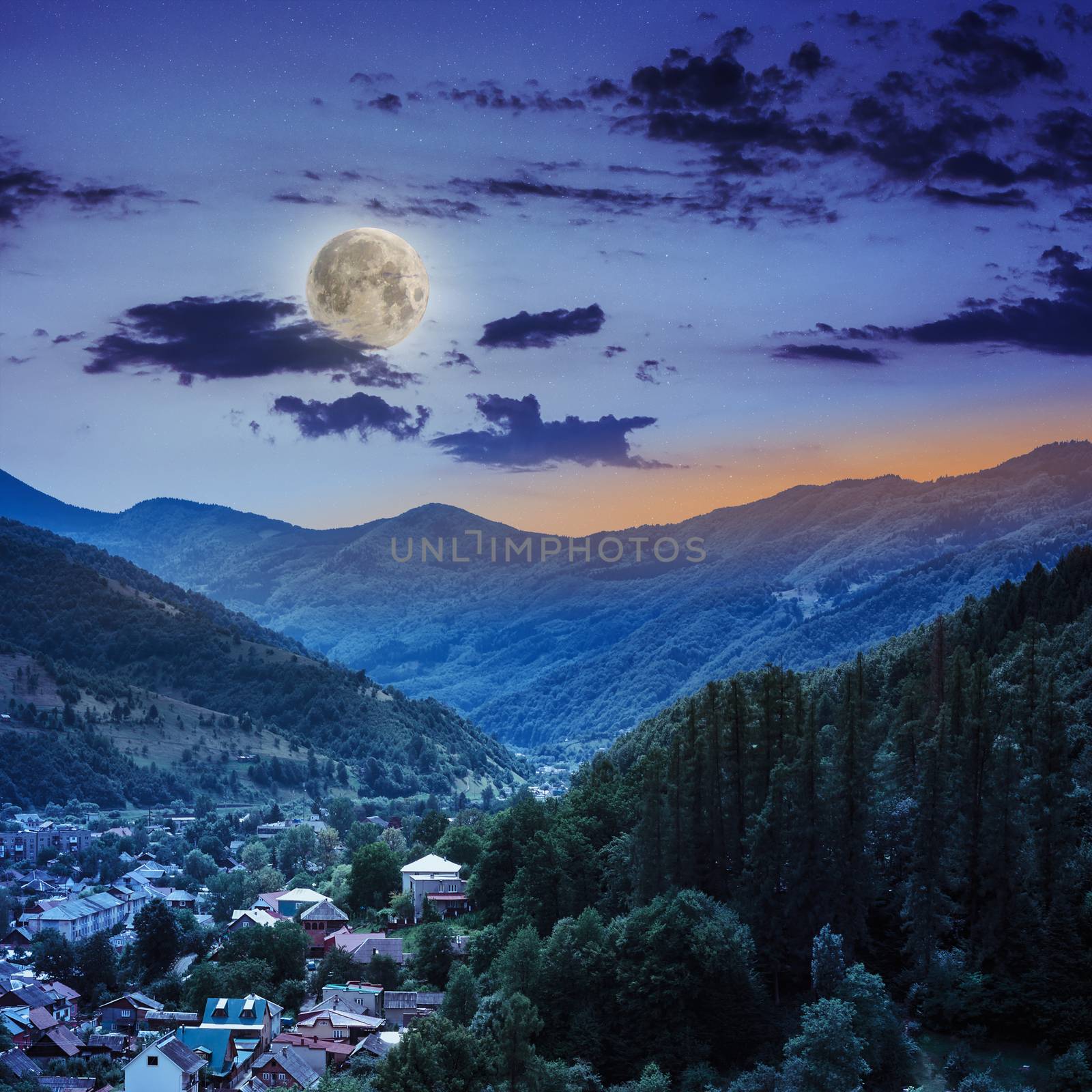 autumn landscape. village on the hillside. forest on the mountain light fall on clearing on mountains at night