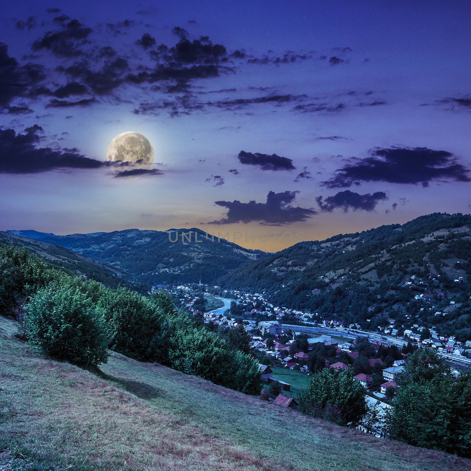 autumn landscape. village on the hillside. forest on the mountain light fall on clearing on mountains in moon light