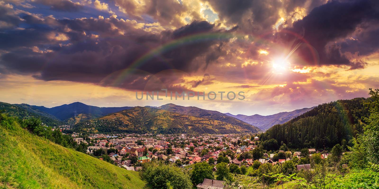 autumn landscape. village on the hillside. forest on the mountain light fall on clearing on mountains at sunset with rainbow