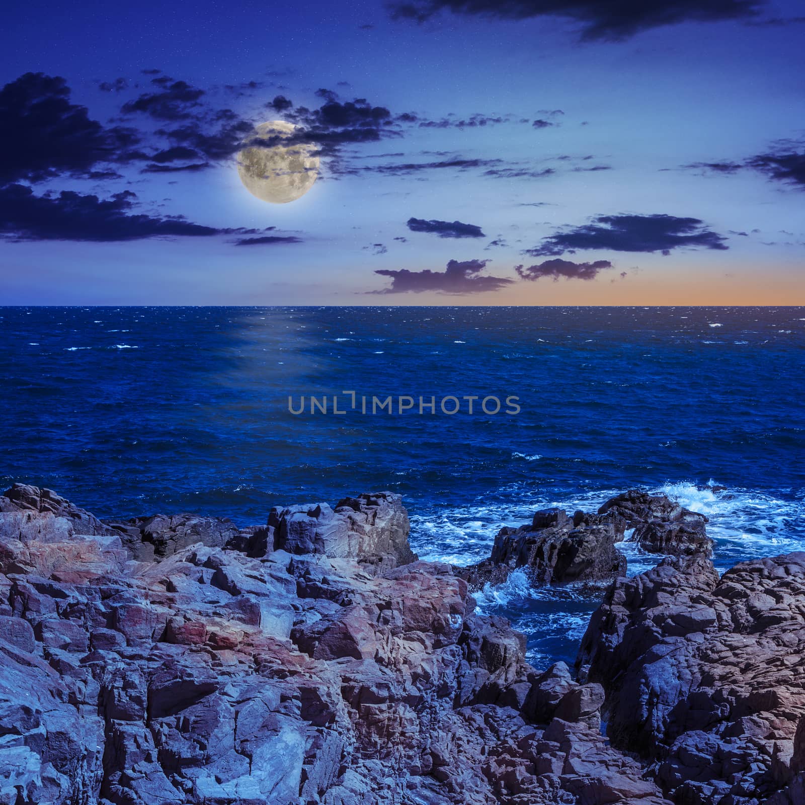 sea ​​wave attacks the boulders and is broken about them at night in moon light