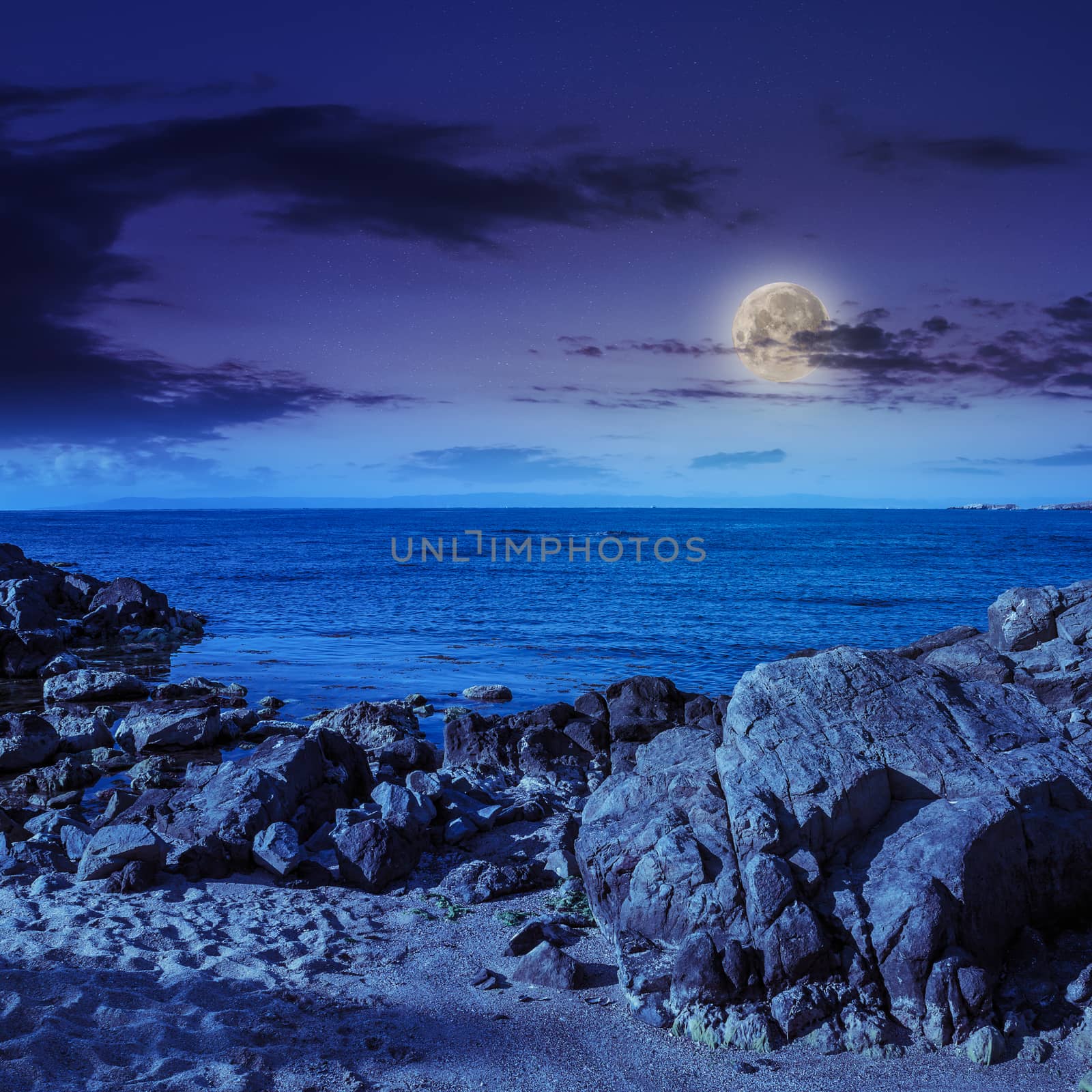 sea wave attacks the sandy beach and break on them at night in moon light