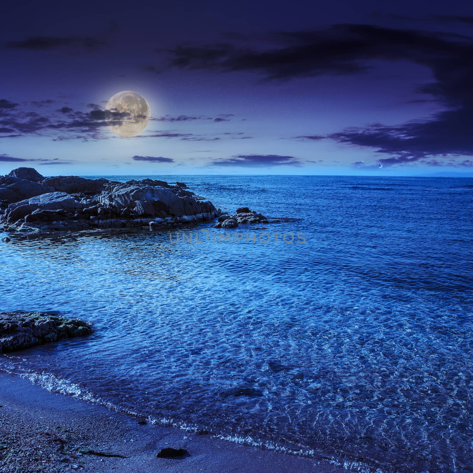 sea wave attacks the sandy beach and break on them at night in moon light