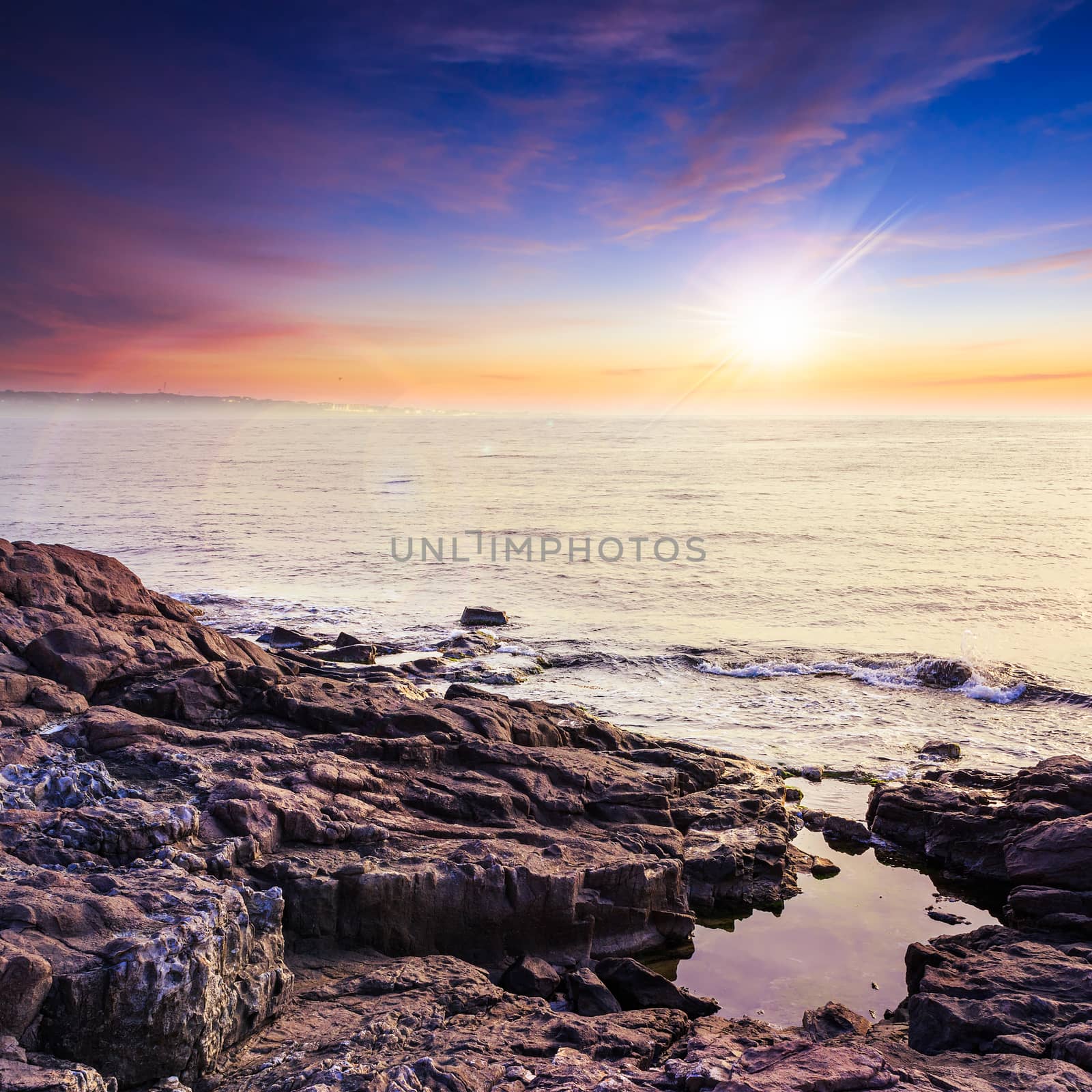 sea wave breaks about boulders at sunset by Pellinni