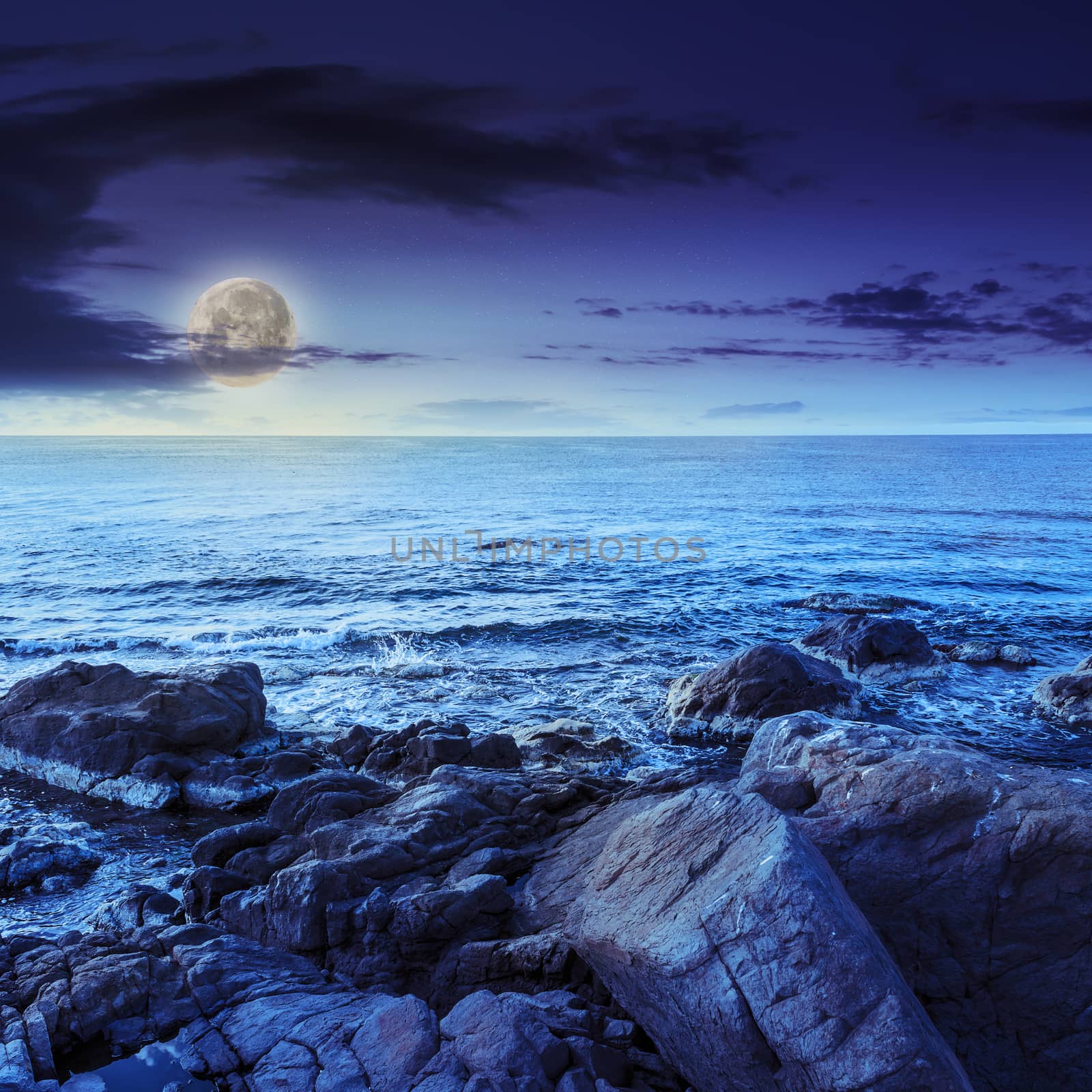 sea wave breaks about boulders at night by Pellinni