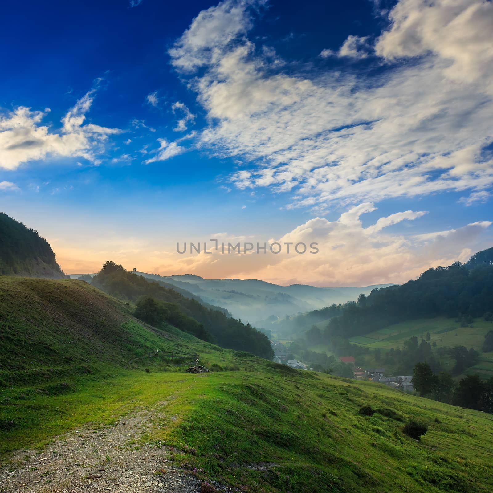 village in cold morning fog with red hot sunrise in the mountains