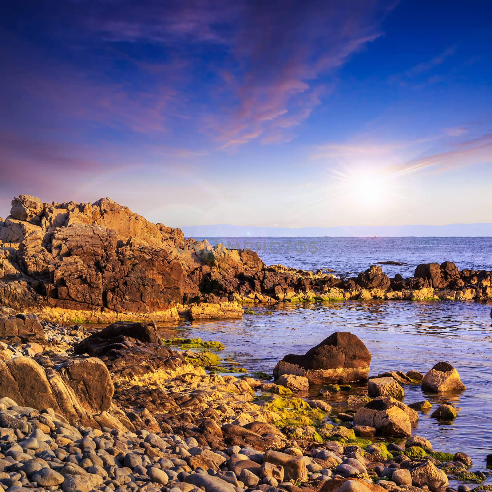 sea wave breaks about boulders at sunset by Pellinni