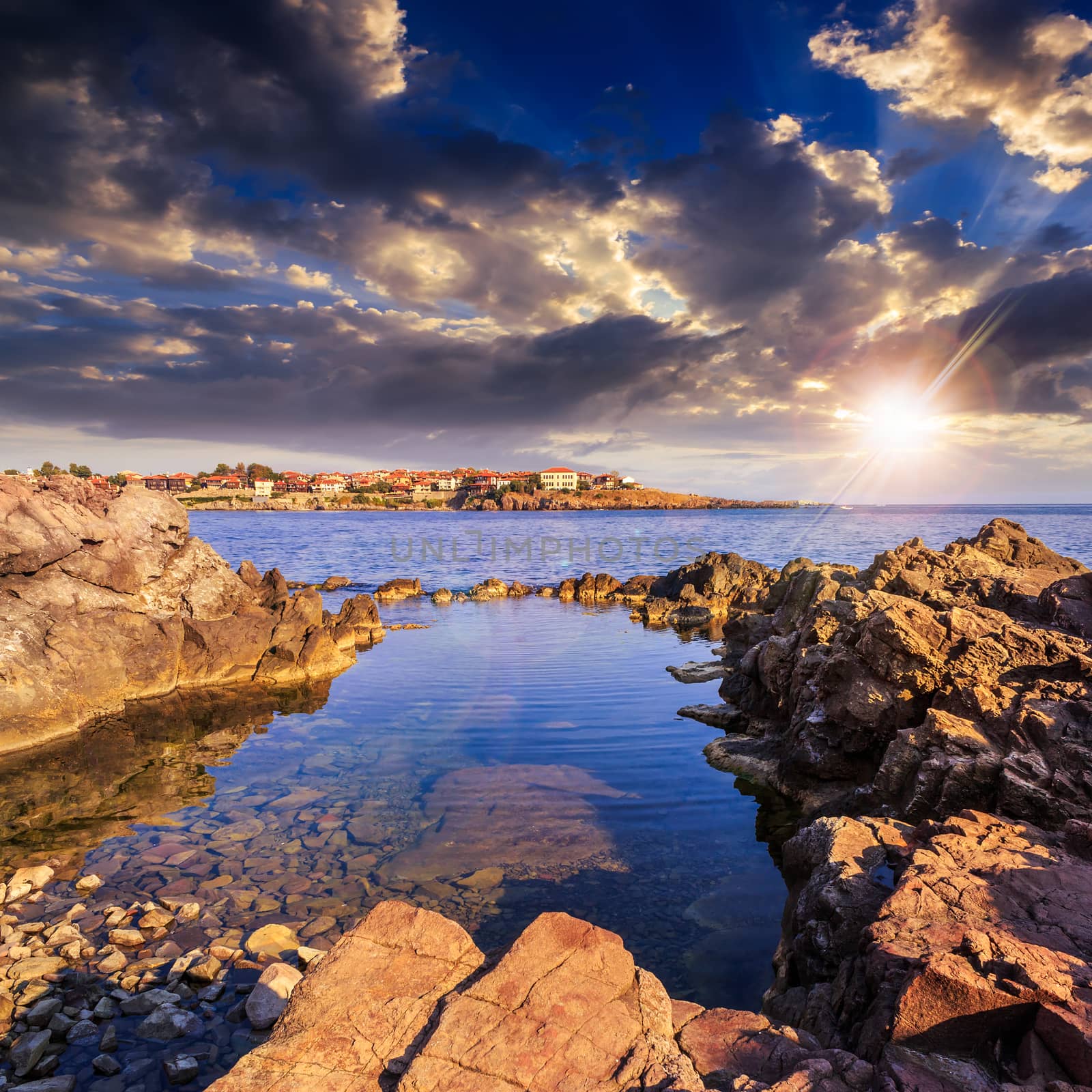 sea coast  with giant boulders against the old city at sunset