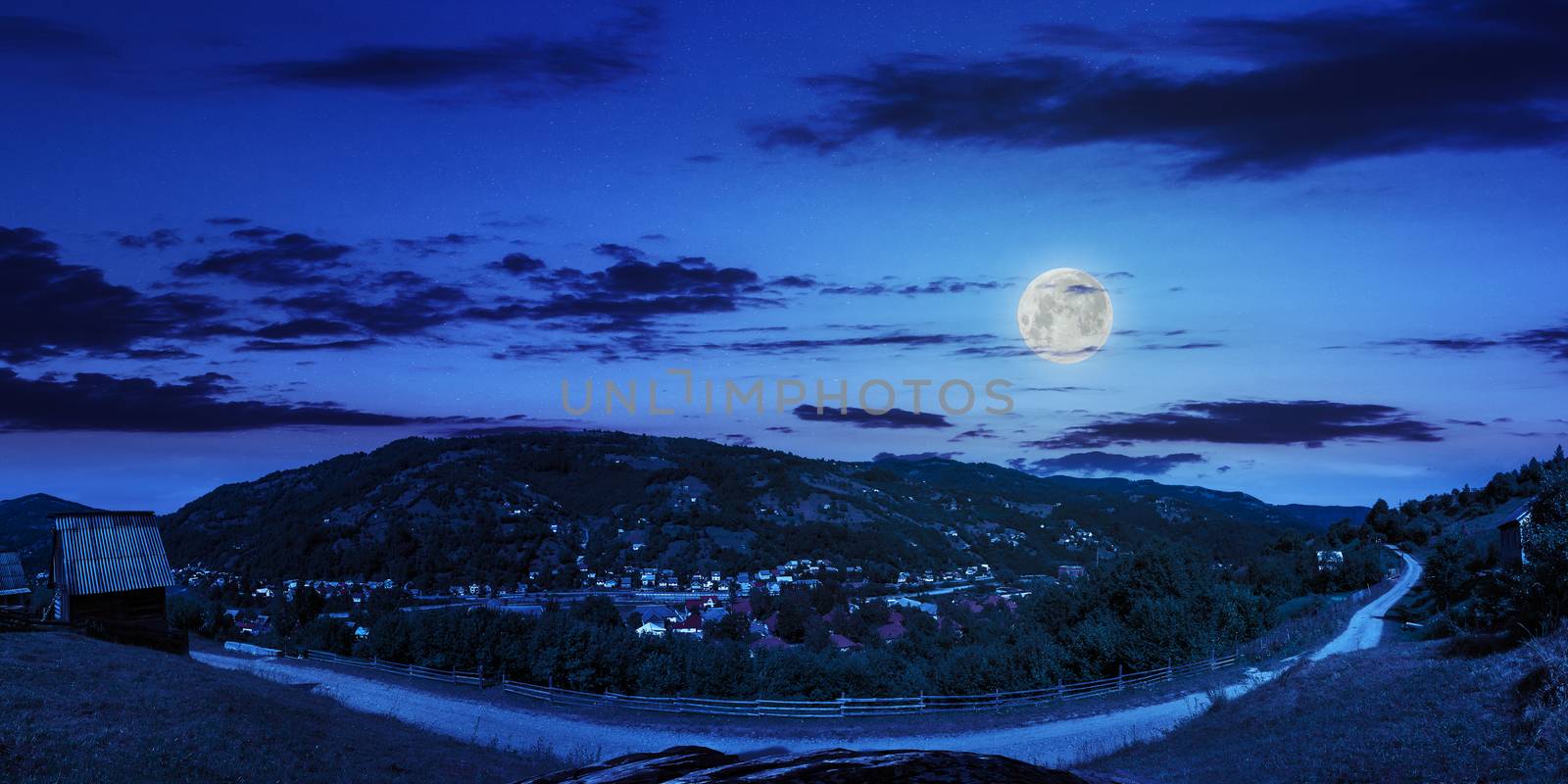 village on hillside of mountain at night by Pellinni