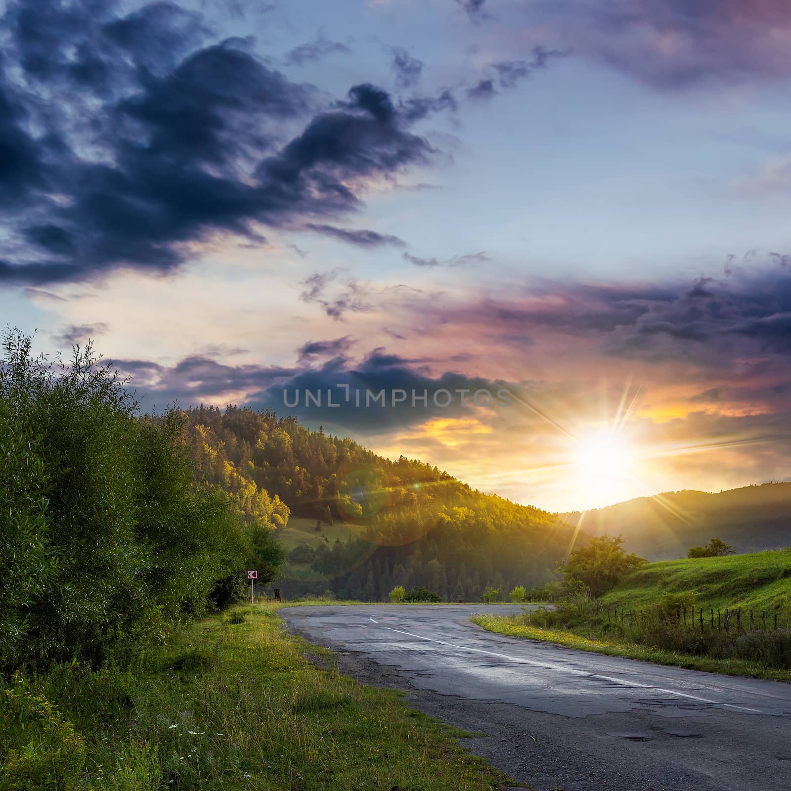 asphalt road going to mountain, passes rural places at ominous sunset after the rain