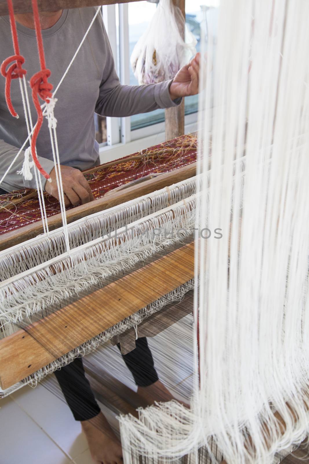 Old asia women demonstrate to procedure of making Thai Silk weaving in small weaving mill