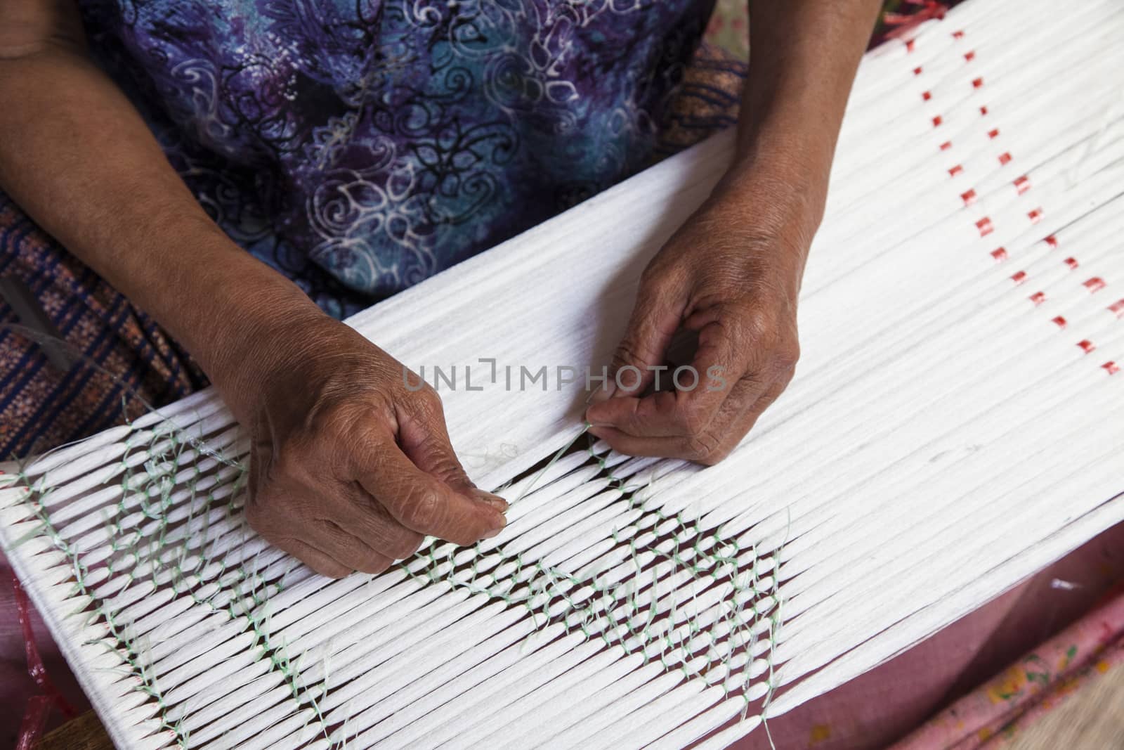 Old asia women demonstrate to procedure of making Thai Silk weaving in small weaving mill