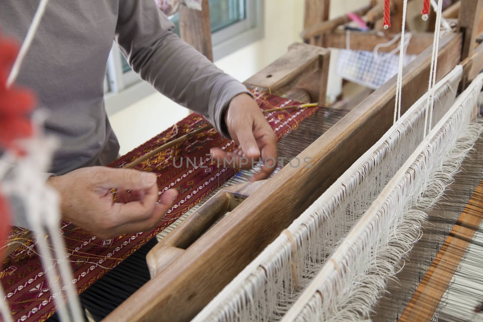 Old asia women demonstrate to procedure of making Thai Silk weaving in small weaving mill