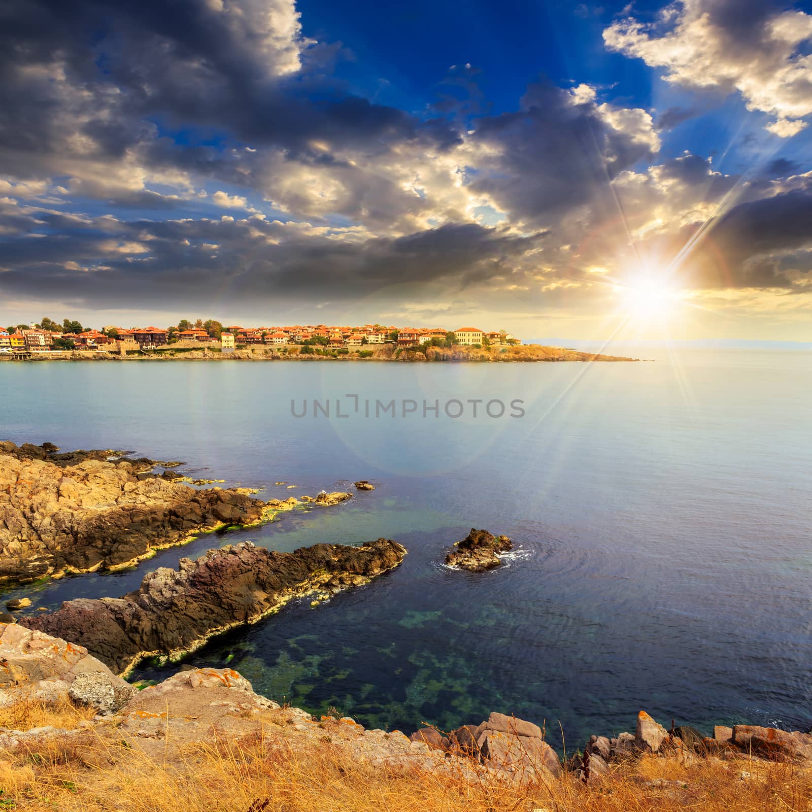 ancient european city on a rocky shore near sea in summer at sunset