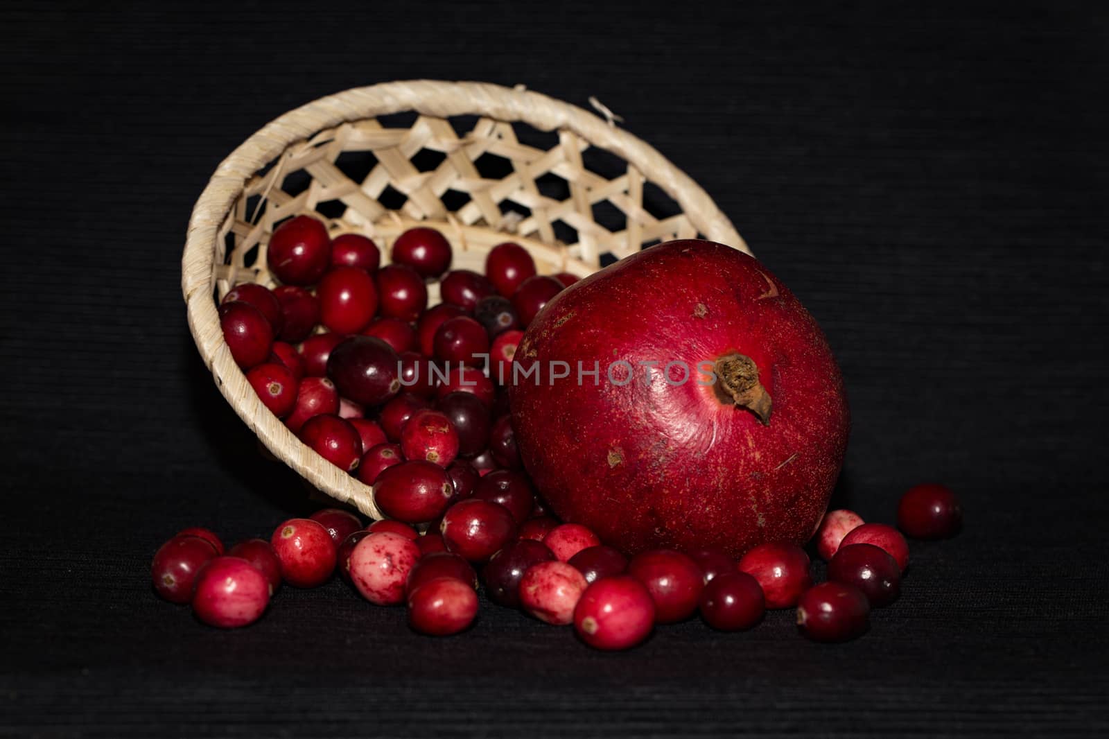 Pomegranate and lingonberry in a wooden basket by boys1983@mail.ru