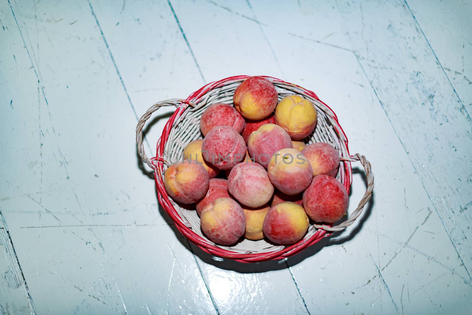 Artificial peaches in a basket on a wooden background