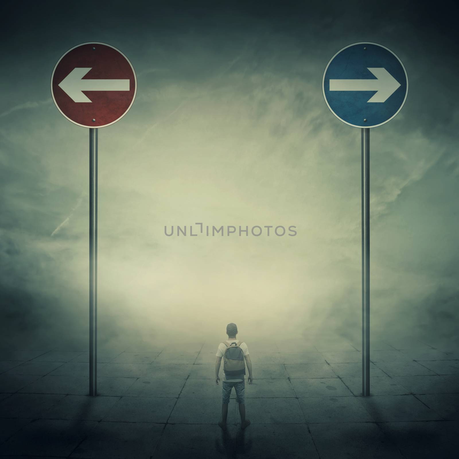 Surrealistic image as a man, with a bag in his back, stand in a foggy street in front of two huge road signs that show the left and right directions. Strategic journey, way of life and intuition concept.