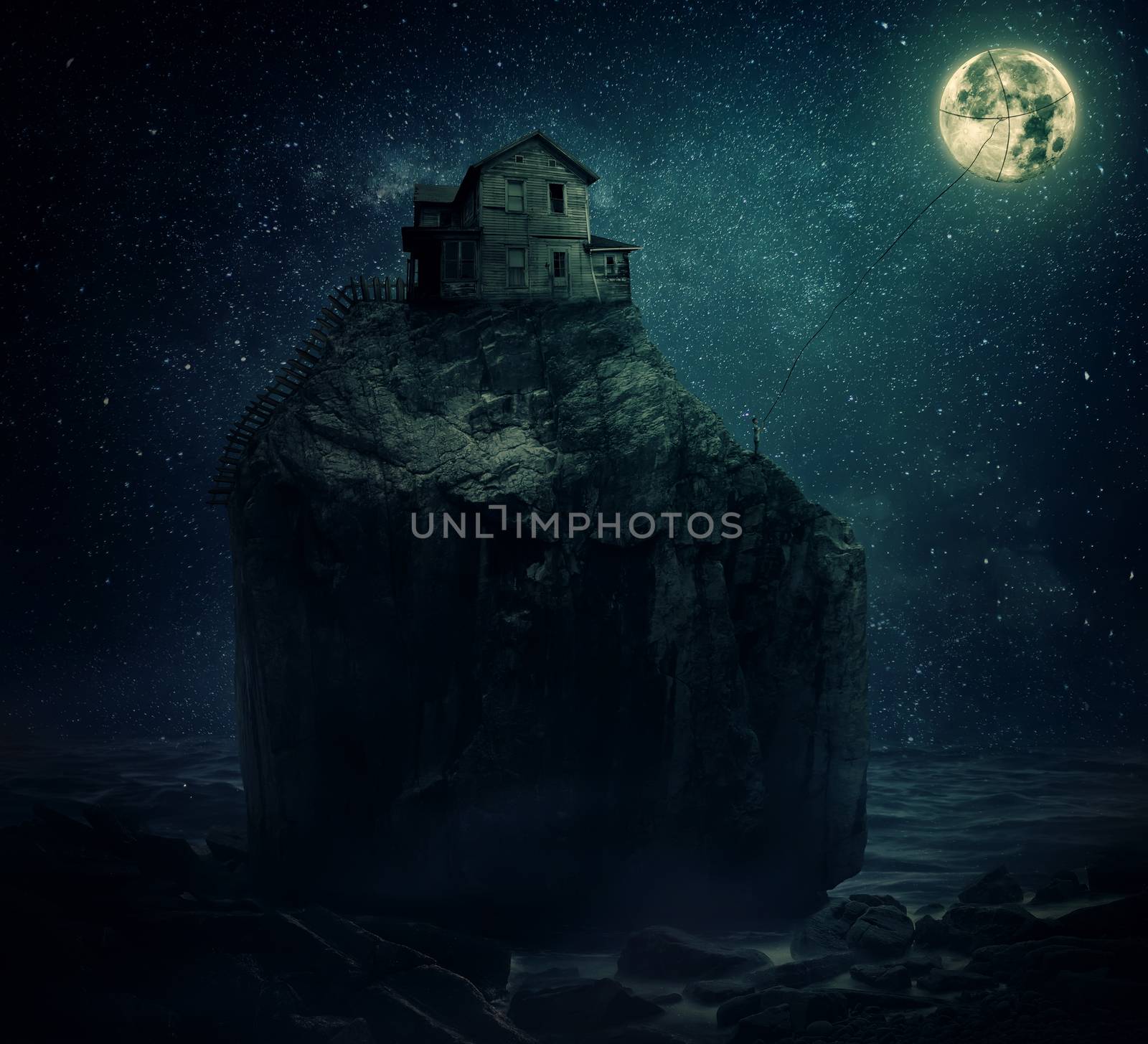 Surreal image with a wood house on the top of a rock hill, near the sea, beyond the starry night sky and a young man, holding a rope, try to catch and pull the full moon.