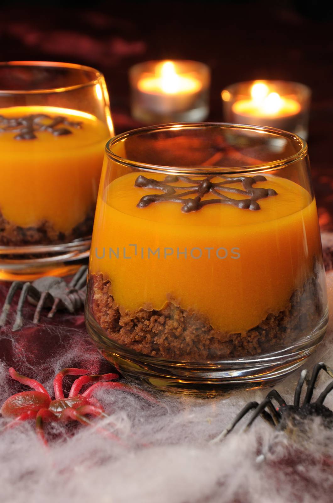 Dessert from biscuit and pumpkin cream in a glass of decorated chocolate  web for Halloween