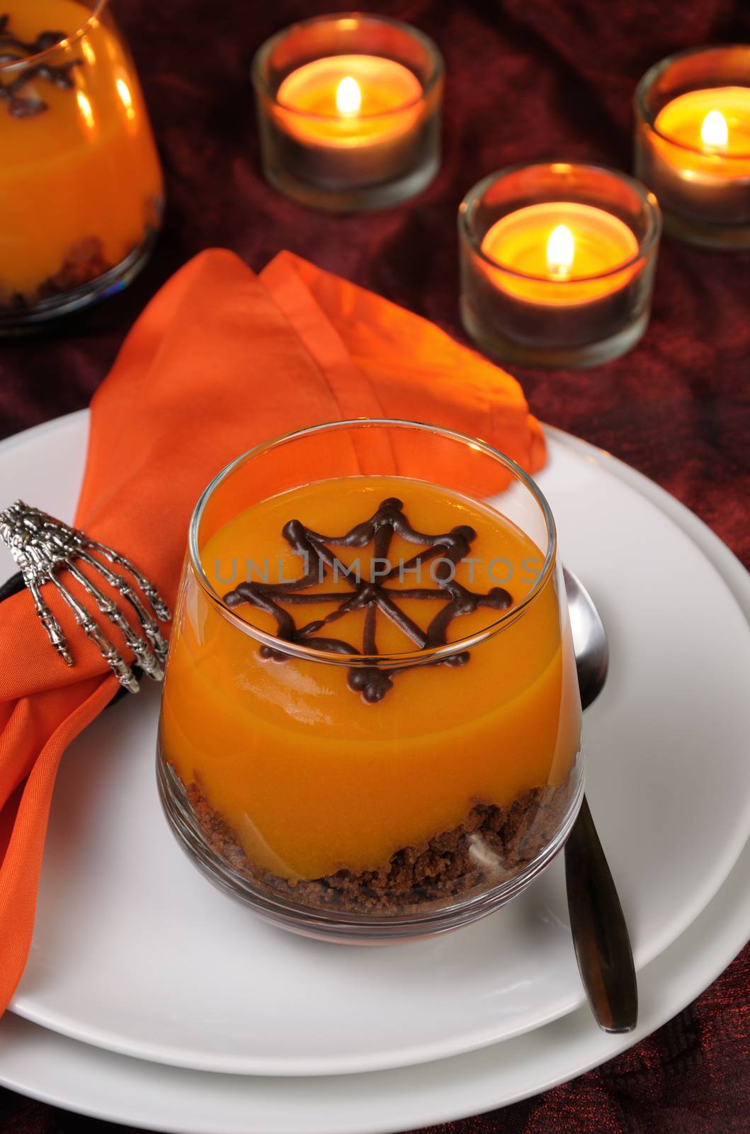 Dessert from biscuit and pumpkin cream in a glass of decorated chocolate  web for Halloween