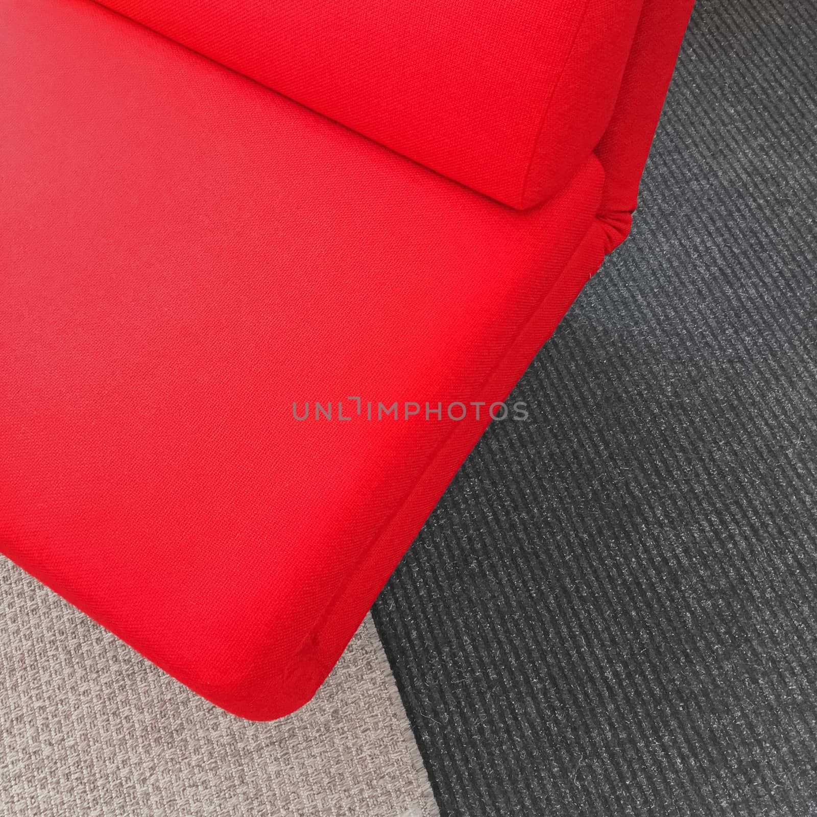 Vibrant soft red chair on gray carpet. Contemporary style furniture.