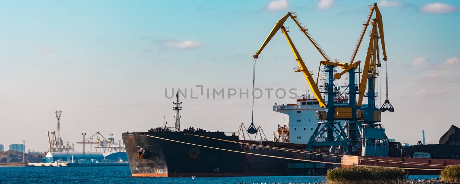 Black cargo ship loading with a coal at the port