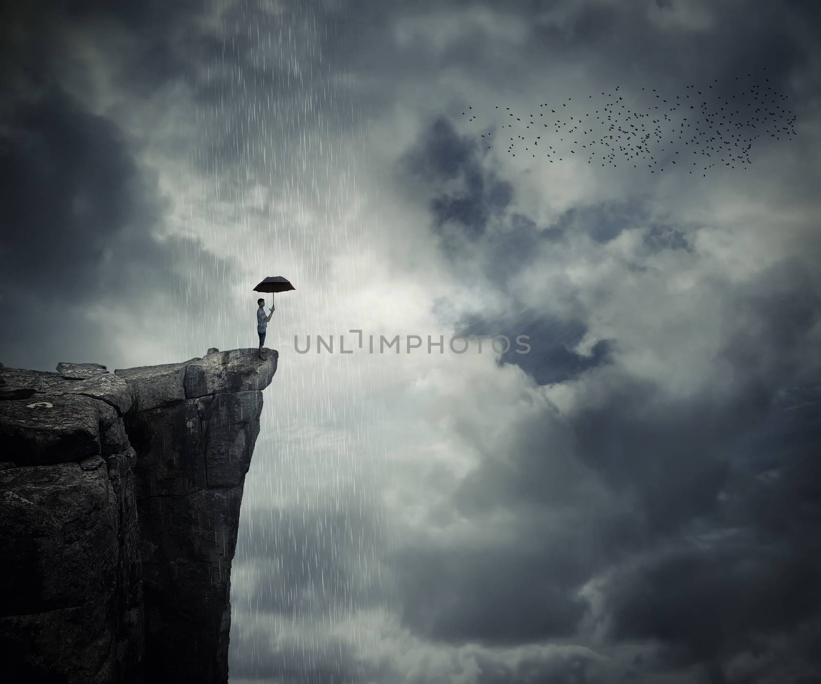 Man with an umbrella stand on the edge of the cliff, calling the rain. Mysterious place above the clouds.