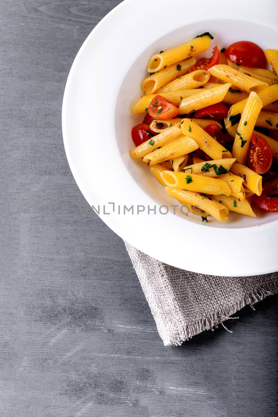 Penne with anchovy and tomato in a white plate