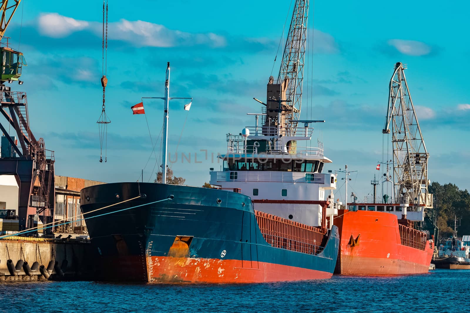 Blue cargo ship moored and loading at the port