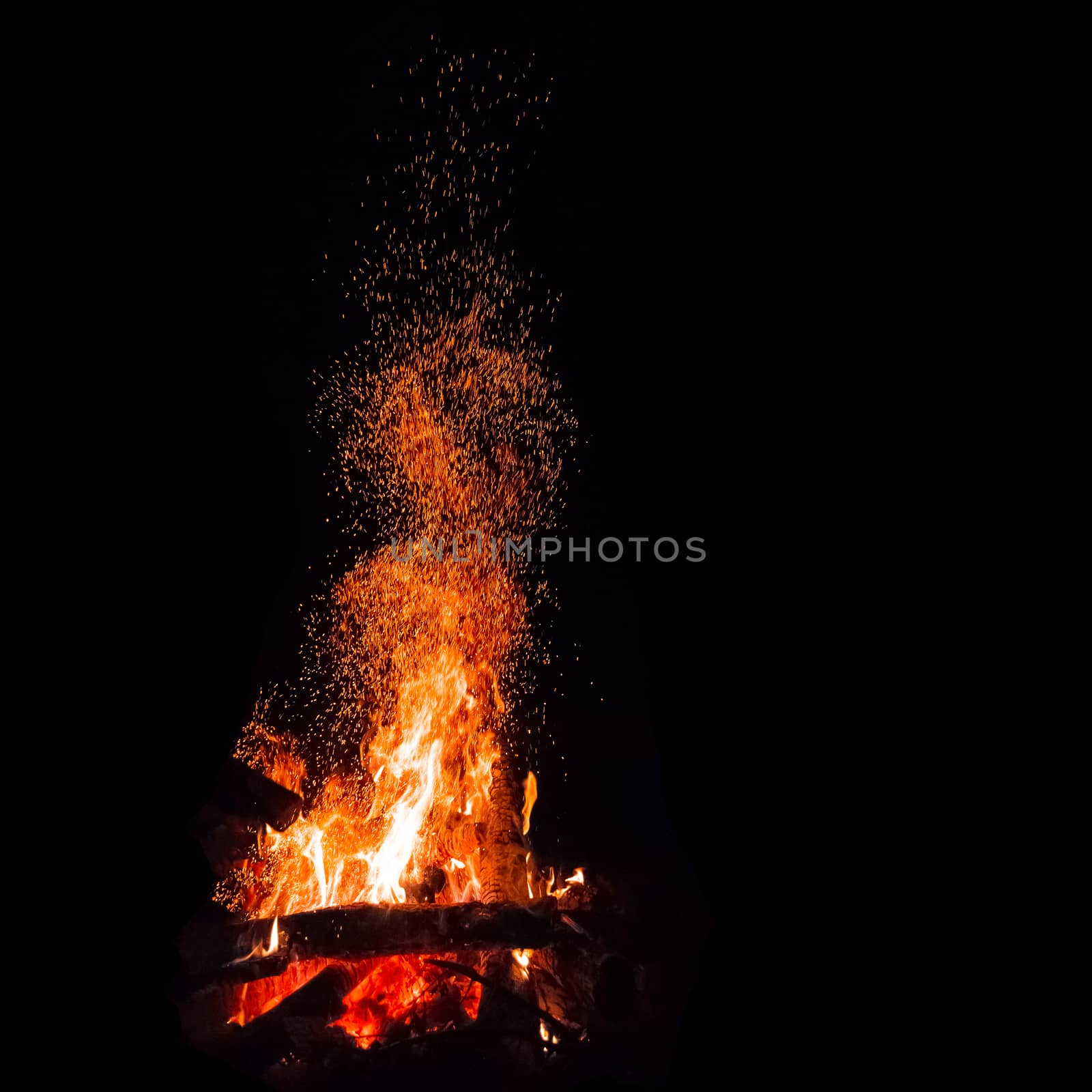 Campfire with flying sparks isolated on black background