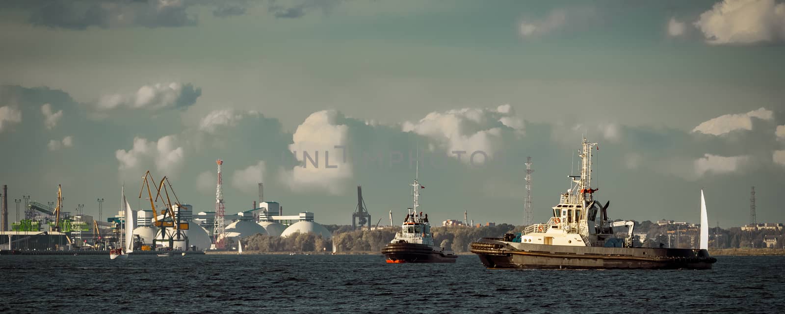 Two tug ships are accepting cargo vessel at Daugava river