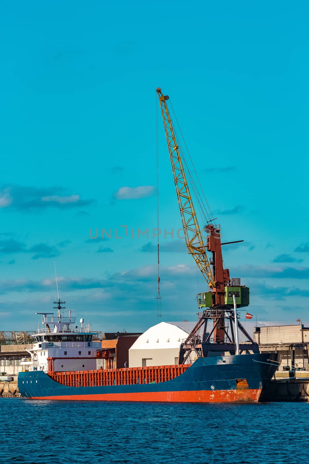 Blue cargo ship moored and loading at the port