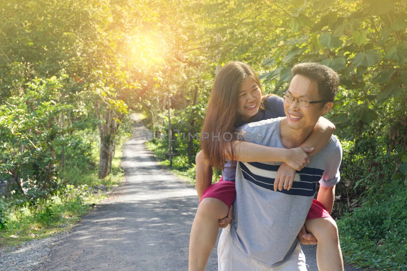 Portrait of man giving a piggyback ride to woman in park on a sunny day                   