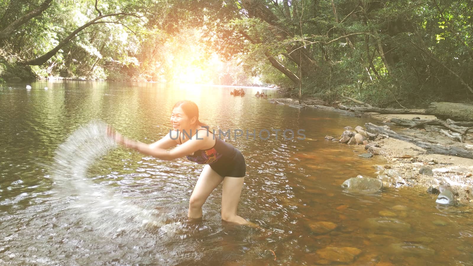 Beautiful girl is playing a river , river surrounded by tropical forest  , with warm sunlight effect.